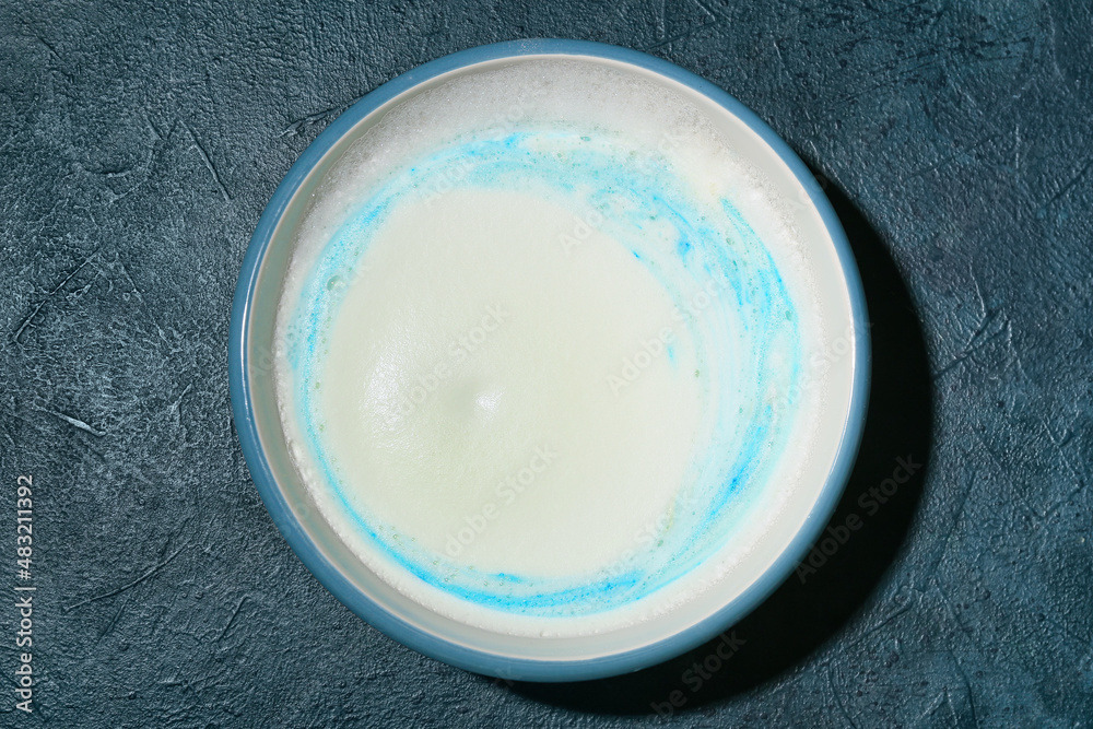 Bath bomb dissolving in bowl with water on black background