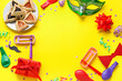 Frame made of hamantaschen and decor for Purim holiday on yellow background