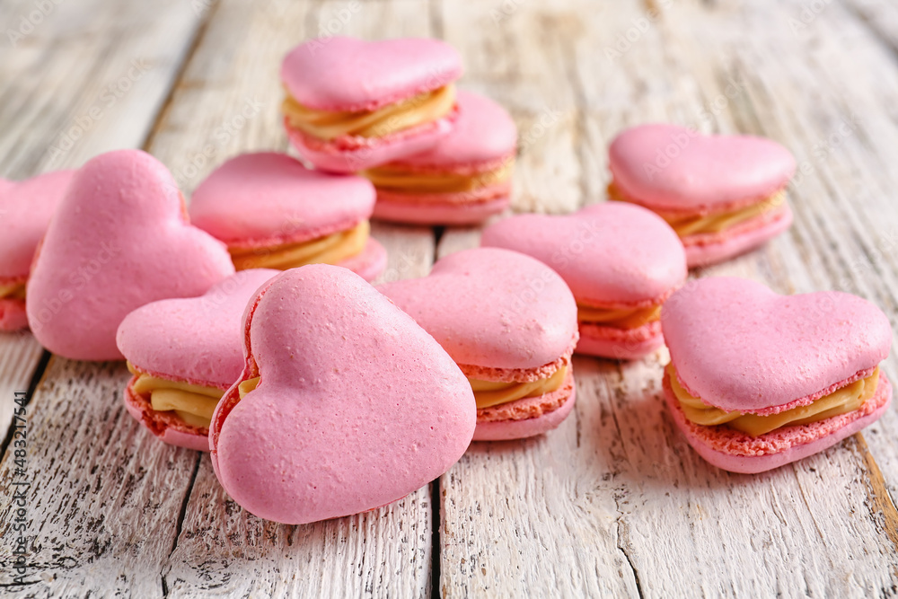 Tasty heart-shaped macaroons on white wooden background