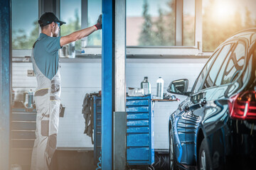 Wall Mural - Car Mechanic Next to Automotive Lift Repairing Station