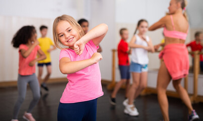 Wall Mural - Portrait of emotional girl doing dance workout during group class in studio