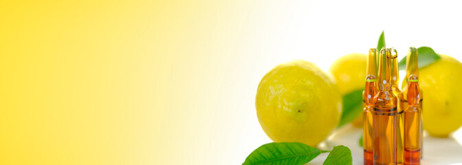 Vitamin C.vitamin banner.Ampoules for injections with vitamin C, lemons fruits with green leaves on a white background with a yellow gradient.Beauty and health banner.Health and medicine concept. 