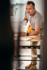 A handsome handyman on his coffee break smiling at the camera