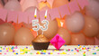 Decorations with balloons and a happy birthday candle with the number 53 for a woman. Happy birthday greetings in pink flowers for fifty-three years old for an adult girl, copy space. Muffin