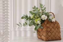 Stylish Wicker Basket With Bouquet On White Table Indoors, Space For Text