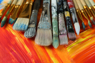 Set of different brushes on abstract colorful paint, closeup