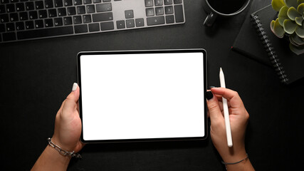 A hipster woman using digital tablet computer on her modern black office table.