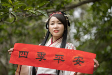 A Young Woman Stand Outdoors And Hold Spring Festival Scrolls To Celebrate Chinese Lunar New Year. Translation For The Text On Scrolls: "All Good All The Time".