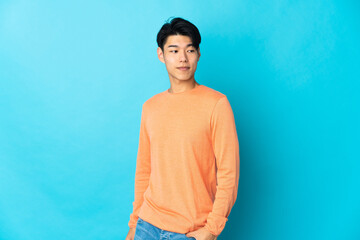 Young Chinese man isolated on blue background . Portrait