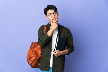 Wall Mural - Young student woman isolated on purple background having doubts