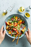 Fototapeta  - Woman’s hands holding bowl with fresh colorful spring vegetable salad - lunch