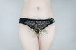 © Siniehina - A woman has small flowers sticking out from under her underpants, imitating extra hair. Laser hair removal and shaving with a razor. Conceptual shot about women issues. Proper self care.