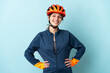 © luismolinero - Young cyclist woman isolated on blue background posing with arms at hip and smiling
