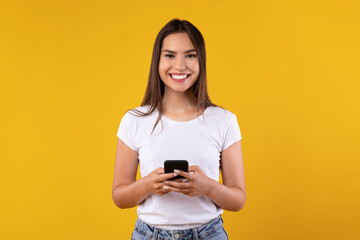 Poster - Happy excited lady using mobile phone at yellow studio