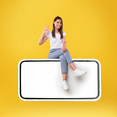 Wall Mural - Woman showing white empty smartphone screen and ok sign