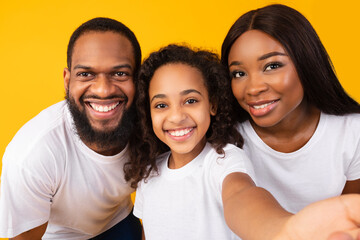 Wall Mural - Portrait of happy black family taking selfie together at studio