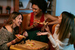 Happy multicultural female friends having party at home and eating pizza.