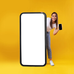 Wall Mural - Woman holding empty smartphone screen, peeking out big panel