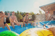 © Impact Photography - Friends having fun splashing water on each other at the swimming pool