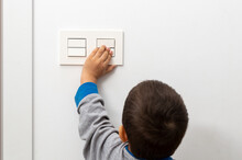 Rear View At Little Careless Child Boy Exploring House Playing Turning Light Switches, Home Electricity Danger Security, Electric Shock Risk And Kids Safety, Energy Power Saving Concept, Copy Space