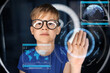 © Syda Productions - future technology, augmented reality and cyberspace concept - happy smiling boy in glasses touching virtual screen projection over white illumination in dark room