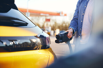 Wall Mural - Man plugging electric car in at a EV charging station