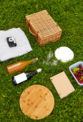 Wall Mural - leisure and summer concept - close up of food, drinks and picnic basket on grass