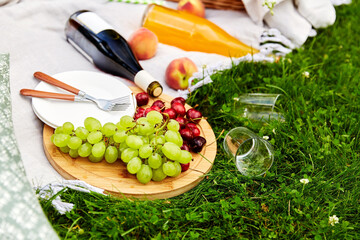 Wall Mural - leisure and drinks concept - close up of food, drinks and basket on picnic blanket on grass