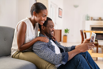 Mature african man and beautiful woman watching movie on digital tablet