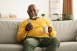 © Prostock-studio - Mature African American Male Using Cellphone Texting Sitting At Home