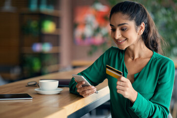 Wall Mural - Happy young lady using mobile phone and credit card