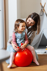 Poster - family, leisure and people concept - happy mother playing with little baby daughter bouncing on hopper ball at home