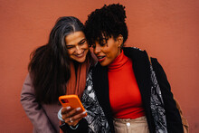 Positive Diverse Ladies Using Smartphone On Red Background