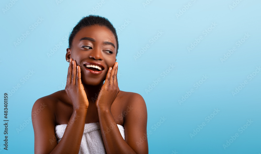 Spa facial concept. Happy black lady touching her soft flawless skin on ...