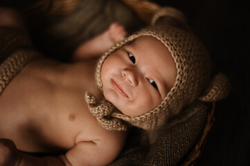 Soft picture of a beautiful baby boy 1-3 months laying on brown bedding in a basket wearing crochet bear crochet costume, newborn photography