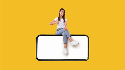 Wall Mural - Woman sitting on white blank smartphone screen showing thumbs up