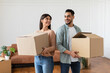© Prostock-studio - Happy millennial couple holding cardboard boxes, relocation concept