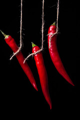 Canvas Print - Red hot pepper on a black background. Hot peppers hang on a rope. ripe vegetable