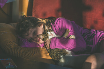 child and cat lying together in bed