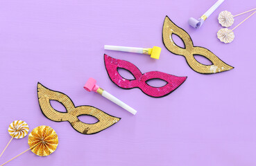 Wall Mural - carnival party celebration concept with mask and colorful party accessories over purple wooden background. Top view. Flat lay