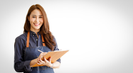 Charming young Asian businesswoman owner wearing an apron holding With clipboard front of an isolated over white background. Looking at the camera.