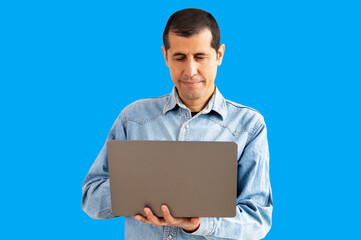 Cropped portrait of handsome young businessman working on his laptop with blue background