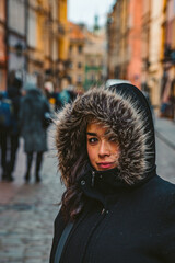 Ethnic Woman Smiles in Fur Hooded Jacket on Historical European Street in Warsaw, Poland