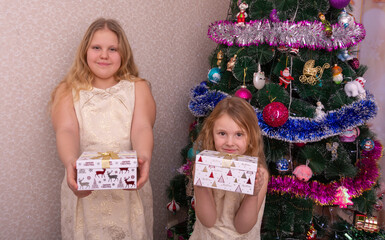 Wall Mural - Two beautiful little sisters near the Christmas tree.