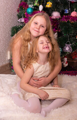 Wall Mural - Two beautiful little sisters near the Christmas tree.