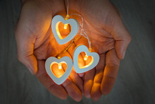 In The Palms Of Men's Hands Lie Three Glowing Yellow Hearts. Valentine's Day Concept. February 14 Is The Day Of All Lovers. Close-up, Top View.