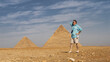 A man stands in the desert against the backdrop of the great pyramids of Cheops and Chephren, looks into the distance and smiles. The arm is thrown behind the head.  Blue sky, clouds. Egypt