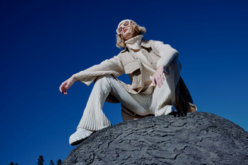 woman sitting on a stone nature blue sky in a hat relaxation