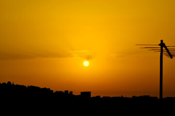 Wall Mural - Orange yellow sunset with the silhouette of an antenna on the right side.
sunset over the city