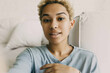 © shurkin_son - Pretty smiling African-American girl making selfie or recording stories for her personal page on social networks, wearing blue clothes with nose jewelry, white interior of bedroom on background
